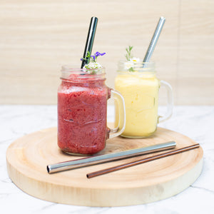 two smoothies with boba tea drinking straws on a wooden display