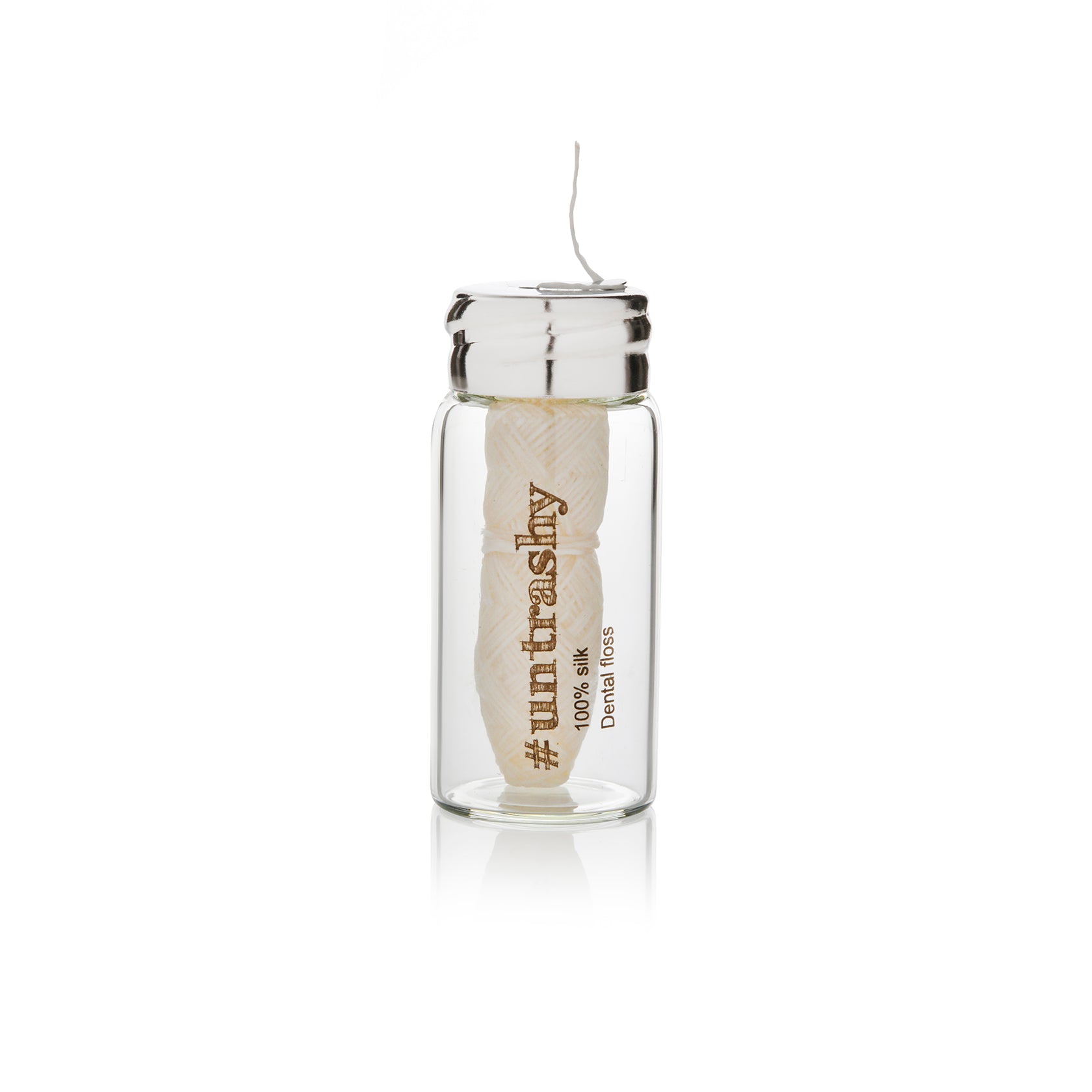 Silk dental floss in a glass jar on a white background